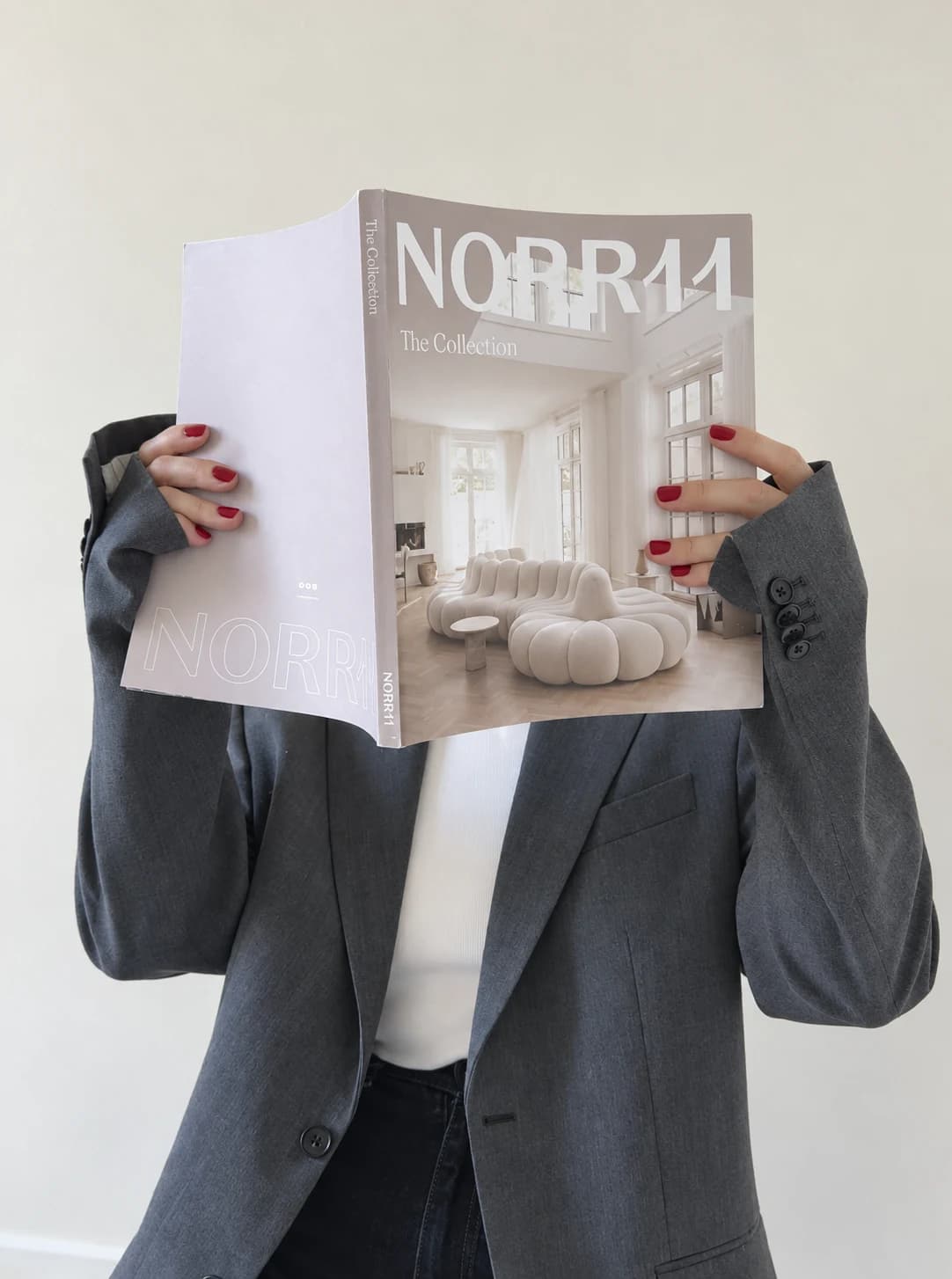 Røde negle og grå blazer med et NORR11-magasin